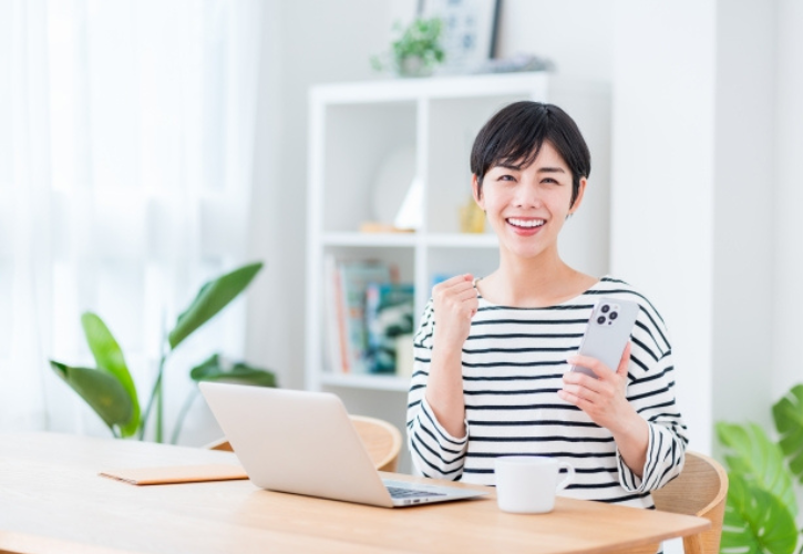 パソコンの前でガッツポーズする女性